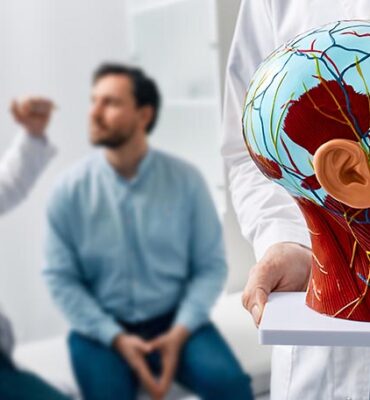 Neurology, conceptual image. Anatomical model of human head with vascular structures and nerves in foreground of neurologist's consultation with patient in hospital